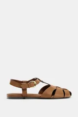 Sandalias estilo cangrejera plana de color marrón, con diseño de tiras entrelazadas en la parte delantera y cierre ajustable mediante hebilla metálica en el tobillo.