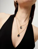 Collar doble dorado con cadena de eslabones y dije de cristal facetado ovalado.