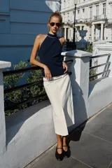 Top halter azul marino con detalles de ribetes en contraste color blanco en el cuello y el borde inferior, de diseño sin mangas y espalda descubierta con cierre de botones en el cuello.