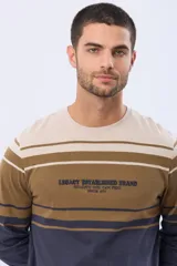 Remera de manga larga con diseño de rayas horizontales en tonos beige, marrón y azul marino. Presenta cuello redondo y un bordado central en relieve con el texto Legacy Established Brand.