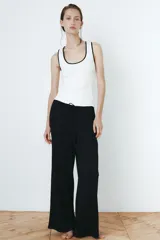 Pantalón de pijama de punto pointelle suave, de color negro, con piernas levemente acampanadas, cintura elástica con ribete de volados y cordón de ajuste.
