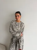 Conjunto de dos piezas compuesto por una remera de manga larga y un pantalón de corte ancho, ambos confeccionados en tela de viscosa con estampado animal print tipo cebra en tonos beige y negro.