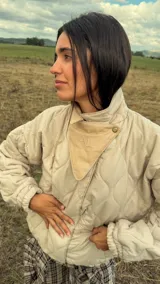 Campera puffer de diseño matelaseado en rombos, color beige. Presenta cuello alto, cierre frontal y solapa triangular decorativa con logo bordado. Posee mangas largas con puños elastizados y ruedo ajustado tipo bomber.