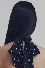 Top de satén con diseño tipo halter, escote alto con frunces frontales y bajo estilo globo. Presenta espalda abierta con cierre de botones forrados en la parte inferior.