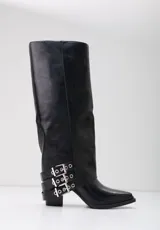 Bota de caña alta color negro, con diseño estructurado y punta fina. Presenta tres correas decorativas con hebillas metálicas plateadas en la zona del tobillo y un taco cuadrado de altura media.