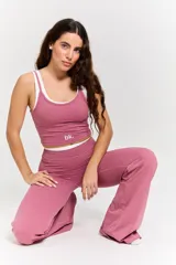 Conjunto deportivo de dos piezas en color rosa, compuesto por un top corto con tirantes finos y logo estampado, y un pantalón de corte acampanado con cintura alta.