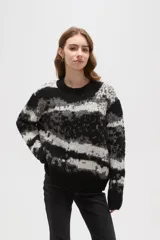 Sweater de tejido jacquard con diseño de rayas irregulares en tonos negro, blanco y gris. Presenta cuello redondo a la base, mangas largas y un corte holgado.
