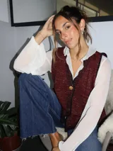 Chaleco tejido color tostado con destellos de lurex, escote en V y cierre frontal con botones. Presenta detalles de bordados y terminaciones en crochet en color crudo.