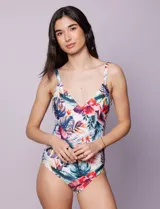 Malla enteriza con escote en V cruzado y breteles finos regulables, confeccionada en tejido estampado con diseño tropical y floral en tonos blancos, fucsias, azules y verdes.