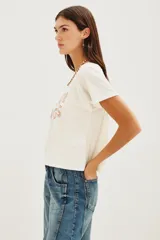 Remera de algodón color crudo con estampa frontal multicolor con la frase 'BOOGIE NIGHTS' en tipografía con efecto arcoíris. Presenta mangas ranglan y cuello redondo.