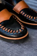 Mocasines de cuero en color dorado con detalles en marrón, con diseño bicolor y costuras artesanales expuestas en el empeine.