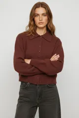 Saco de punto color bordó con cuello tipo camisa, cierre frontal con botones y mangas largas con puños acanalados.