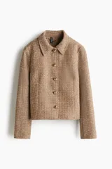 Chaqueta corta de tejido texturizado en color tostado, con cuello camisero, cierre frontal de botones metálicos dorados y diseño entallado con costuras moldeadoras.