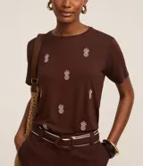 Blusa marrón de mangas cortas, confeccionada en viscosa, con cuello redondo y bordados de piñas en la parte delantera.