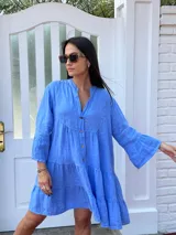 Vestido corto de lino azul vibrante, con cuello mao y cierre frontal de botones. Presenta un corte amplio con volados en el cuerpo y mangas largas acampanadas.