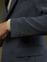 Blazer de corte clásico en color verde oliva con textura jaspeada. Presenta solapas de muesca y cierre frontal con botones.