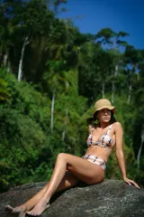 Conjunto de bikini de dos piezas confeccionado en lycra brillante con estampado tie-dye en tonos naranja, negro y blanco. El corpiño es de estilo triángulo con breteles anchos fijos y pinzas para mayor volumen. La bombacha es de tiro medio con cobertura clásica.