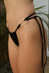 Bombacha de bikini colaless negra, con argollas decorativas de resina color hueso en los laterales.