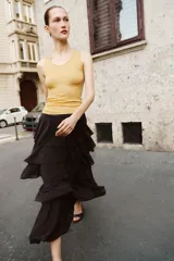 Falda midi de tiro medio con cintura elástica y diseño de múltiples volantes en capas. Presenta un bajo asimétrico y una caída fluida.