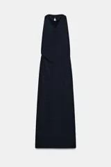 Vestido largo de corte fluido con cuello halter y espalda descubierta. Presenta un detalle de drapeado lateral y bajo recto.