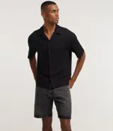 Bermuda masculina de corte recto confeccionada en denim de algodón, con cintura fija, trabillas para cinturón, cierre tradicional y bolsillos laterales y traseros.
