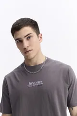 Remera de manga corta color gris oscuro, con escote redondo, ajuste regular y estampado frontal con la palabra "POSITIVE" en estilo graffiti.