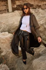 Tapado de silueta recta con estampado de cuadros, escote en V profundo y cierre frontal con un único botón. Presenta mangas largas con leve volumen, tajos laterales y terminaciones con flecos en el ruedo.