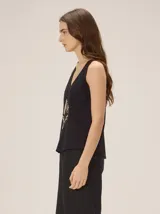 Musculosa de algodón color azul marino, con escote en V y un bordado artesanal de flor en el frente con contorno naranja y relleno dorado.