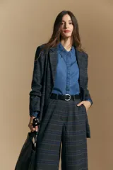 Camisa de denim azul con cuello camisero, cierre frontal de botones y mangas largas abullonadas con hombros fruncidos.
