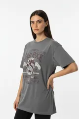 Remera de algodón de manga corta y cuello redondo, con diseño holgado y estampado frontal con motivos florales y texto.