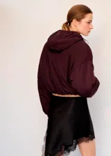 Chaqueta puffer corta color bordó, con capucha ajustable, cierre frontal y bolsillos laterales, de mangas abullonadas y diseño holgado.