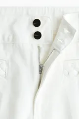 Pantalón jean de denim de algodón rígido, color blanco, de corte wide leg con tiro alto, bolsillos delanteros con ribete trenzado y pliegues marcados.