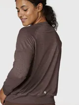 Polera de manga larga con cuello redondo, confeccionada en tejido suave y ligero de efecto melange. Presenta puños elásticos y una banda elástica en la cintura para un ajuste cómodo, con un pequeño logo bordado en el pecho.