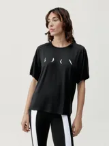 Camiseta deportiva negra de manga corta y corte holgado, con un estampado minimalista en blanco en el pecho que simula fases lunares o un logo abstracto.