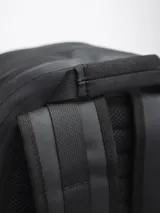 Mochila negra impermeable de estilo moderno y estético, con diseño opaco. Cuenta con compartimento principal con funda acolchada para computadora, varios bolsillos organizadores internos y bolsillos externos con cierre a los lados. Incluye correas ajustables con broche frontal para mayor estabilidad.