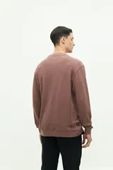 Buzo de felpa gris oscuro, con textura de tejido waffle o gofrado. Presenta cuello redondo, manga larga y un pequeño logo bordado en el pecho.