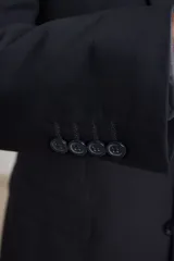 Traje de corte clásico compuesto por saco de dos botones y pantalón de vestir a juego. El saco presenta solapas tradicionales y bolsillos con solapa, mientras que el pantalón tiene un corte recto y formal.