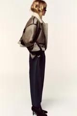 Pantalón de tiro alto y corte tobillero, confeccionado en tejido de aspecto denim oscuro. Presenta diseño de pinzas frontales, bolsillos laterales y cierre frontal con cremallera, botón y gancho. Incluye un cinturón fino a tono con hebilla metálica dorada.