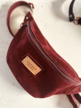 Riñonera de cuero color borgoña con correa ajustable.