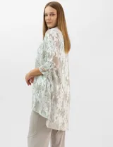 Conjunto de tres piezas compuesto por una musculosa de escote redondo, un cardigan abierto de mangas 3/4 y un pantalón de pierna ancha. La musculosa y el cardigan presentan un estampado abstracto con hilos metalizados, mientras que el pantalón es de color liso con cintura elástica.