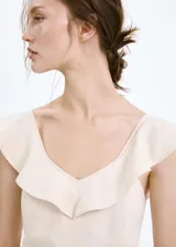 Vestido midi de mezcla de lino y viscosa en color beige, con diseño evasé, cuello en V con volantes decorativos, tirantes anchos y cierre de cremallera lateral.