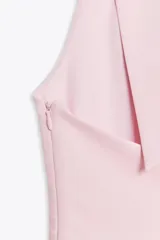 Top negro con cuello halter y escote en pico. Se ata con lazo en la espalda y tiene cierre lateral con cremallera oculta.