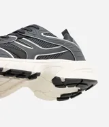Championes estilo dad sneaker de color gris oscuro, con detalles en blanco y líneas plateadas reflectivas. Combinan malla y paneles sintéticos con una suela voluminosa blanca y negra.
