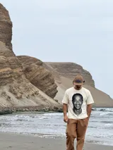 Remera de algodón color beige con estampa fotográfica frontal de Ronaldinho en blanco y negro. Presenta un corte boxy oversize, cuello redondo y mangas cortas.