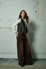 Jean de corte wide leg en color gris lavado, con diseño de aberturas laterales decoradas con tachas metálicas a lo largo de toda la pierna.