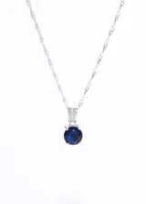 Collar de plata 925 con cadena tipo torsada y dije colgante. El dije consiste en una piedra central redonda de zirconia azul intenso, engastada en un soporte rectangular adornado con pequeñas piedras de zirconia transparentes.