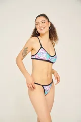 Corpiño de bikini con estampado geométrico en tonos lila, verde y blanco, con breteles finos cruzados en la espalda.