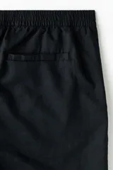 Short negro de corte regular fit, confeccionado en mezcla liviana de lino y algodón. Posee cintura elástica con cordón de ajuste, bragueta con botón, bolsillos en las costuras laterales y un bolsillo ojal en la parte posterior.