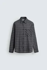 Camisa de corte relajado confeccionada en voile de algodón, con estampado de cuadros. Presenta cuello solapa, manga larga con puños abotonados, bolsillo de parche en el pecho y cierre frontal de botones.