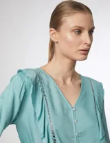 Blusa verde pastel con escote en V, cierre frontal con botones y volados con detalles calados en el frente y las mangas.